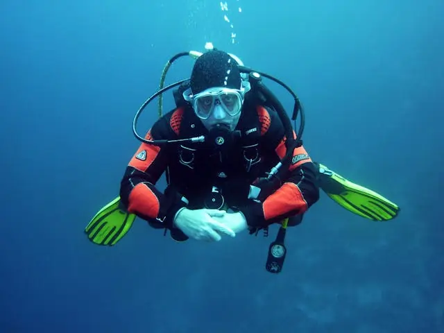 Scuba diver in an orange wetsuit hovering in clear blue water